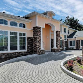 A modern, elegant house with a landscaped driveway and stone accents.