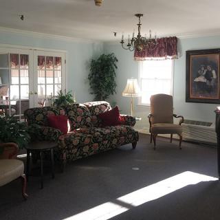 A cozy living room with a floral sofa, chairs, and decorative elements.