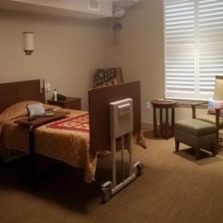 A well-furnished hospital room with a bed, chair, and table next to a window.