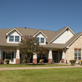 A suburban residential house with a well-maintained lawn under a clear blue sky.