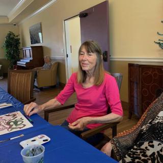 A woman engaged in an art activity at a table indoors.