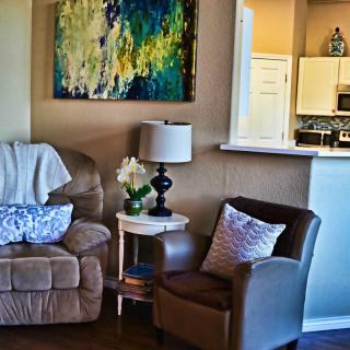 A cozy living room corner with a sofa, armchair, and decorative artwork.
