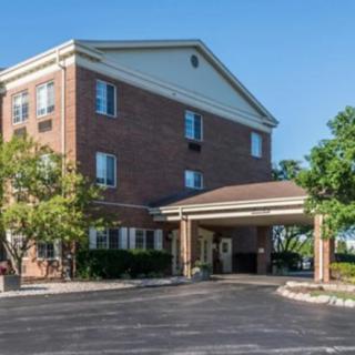 A brick building with a covered entrance and surrounding trees, likely a hotel or similar establishment.