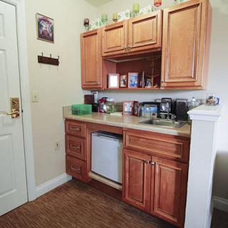 A small kitchen area with wooden cabinets, a sink, and various appliances on the countertop.