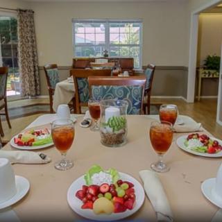 A dining room table set with fruit plates and iced tea, ready for a meal.