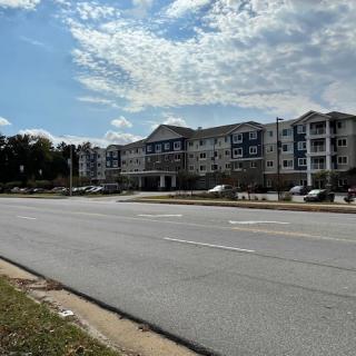 A view of a residential building along a quiet road under a partly cloudy sky.