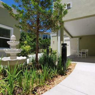 A serene courtyard featuring a central fountain surrounded by lush greenery and a paved walkway.