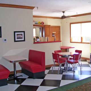 A retro-style diner with red booths, checkered flooring, and a cozy dining area.