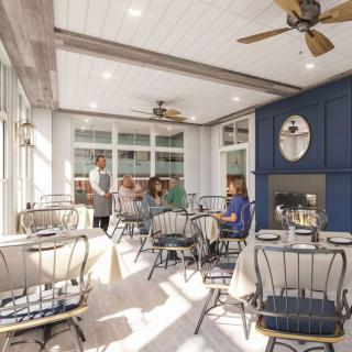 A cozy restaurant dining area with tables set for guests, featuring elegant decor and ceiling fans.