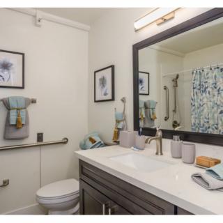 A modern bathroom with a large mirror, sink, and decorative elements.