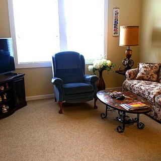 A cozy living room with a blue armchair, floral sofa, and a wooden coffee table.