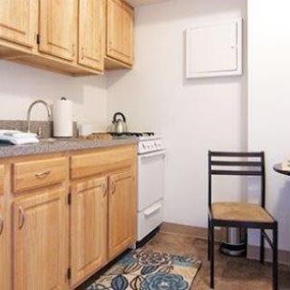 A compact kitchen setup with wooden cabinets, a small stove, and a dining area.