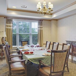 A well-decorated dining room with a large table set for dinner, featuring elegant chairs and a chandelier.