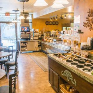 A cozy cafe interior with tables and chairs, a coffee counter, and warm lighting.