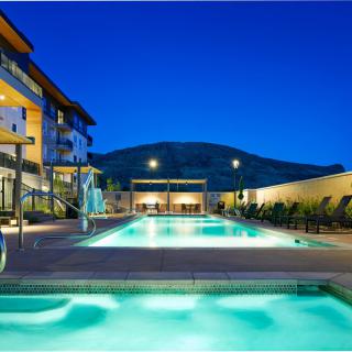 A luxurious outdoor swimming pool at a hotel in the evening, surrounded by modern architecture and scenic views.