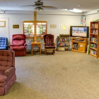 A cozy living room with armchairs, a television, and bookshelves.