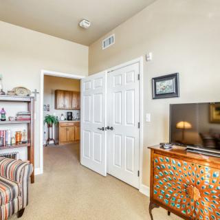 A cozy living room with a television on a decorative cabinet, bookshelf, and a partially open door leading to another room.