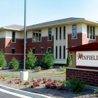 An exterior view of the Winfield residential building, showcasing its modern architecture and landscaped surroundings.