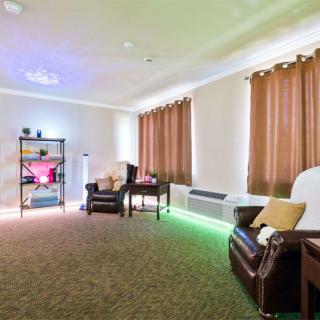 A cozy living room with two chairs, warm lighting, and floor-length curtains.
