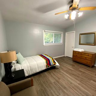 A minimalist bedroom with a single bed, wooden flooring, and modern furniture.