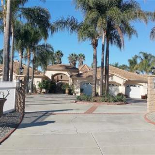 A sunny view of a gated residential home surrounded by palm trees.