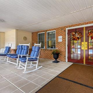A welcoming entrance with rocking chairs and festive wreaths on double doors.