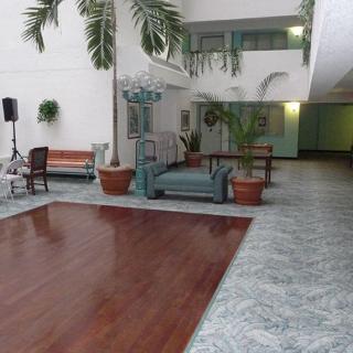 A spacious lobby area with seating, plants, and a wooden floor.