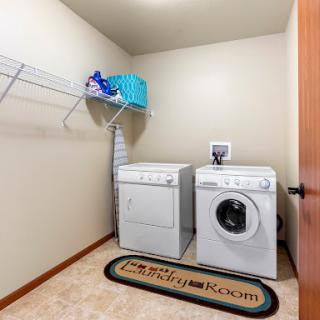 A well-organized laundry room featuring a washer and dryer, with shelves for storage and cleaning supplies.