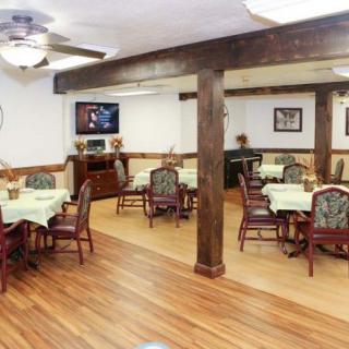 A cozy dining room with several tables and chairs, featuring a television and decorated walls.