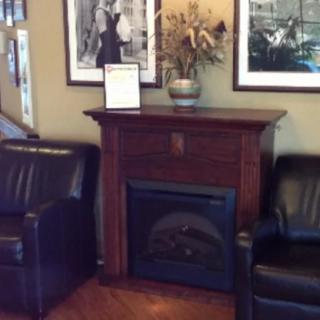 A cozy living room setup with a fireplace flanked by leather chairs and adorned with artwork.