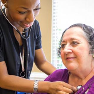A healthcare professional using a stethoscope to examine a patient during a medical consultation.