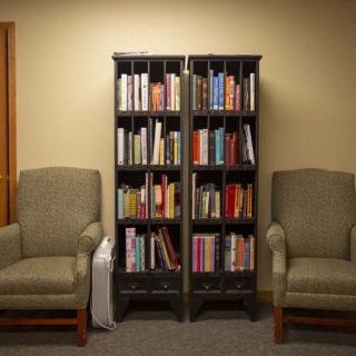 A cozy reading area with a bookshelf flanked by two comfortable chairs.