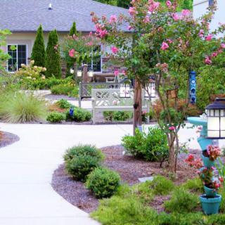A beautifully landscaped garden with a winding pathway surrounded by flowers and shrubs.