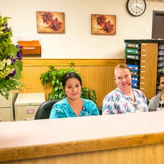 A friendly reception area with three staff members at their desks.