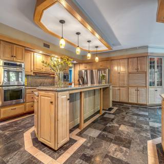 A modern kitchen with wooden cabinets, an island, and pendant lighting.