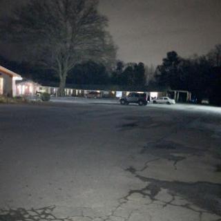 A quiet, dimly lit parking lot at night, surrounded by trees and buildings.