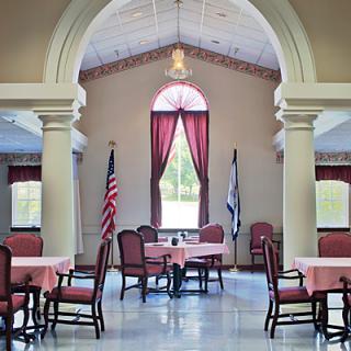 A bright dining area with elegant archways and flags, featuring tables and chairs arranged under natural light.