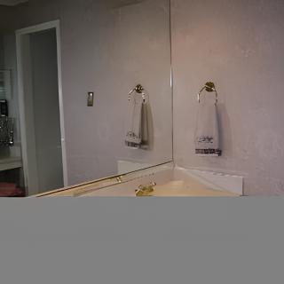 A bathroom with a mirror, sink, and a towel hanging on the wall.