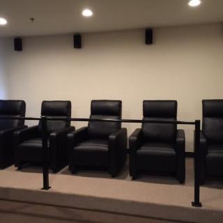 A row of black recliner chairs in a home theater setting.