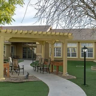 A cozy outdoor patio area with a pergola and seating, surrounded by well-maintained landscaping in front of a building.