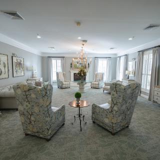 An elegantly designed living room with plush chairs arranged in a cozy setting and a central chandelier.