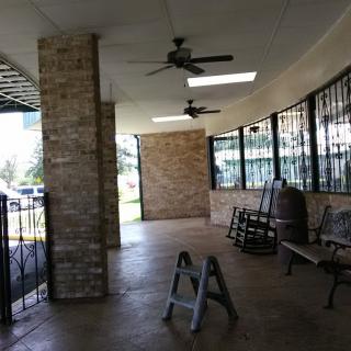 A covered porch area with brick pillars, ceiling fans, and benches.