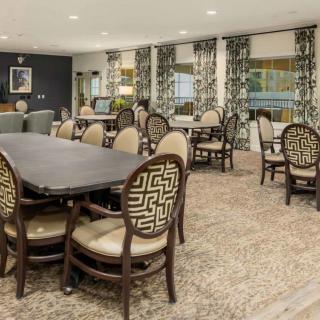 A well-furnished dining room with elegant chairs and tables, complemented by patterned curtains and carpet.