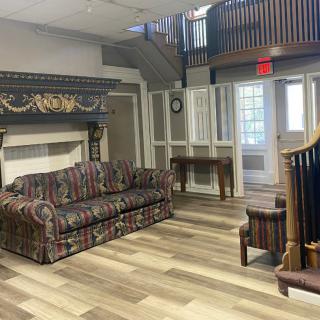 A traditional living room with a patterned couch, fireplace, and wooden flooring.