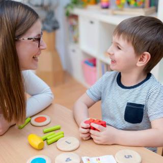 A child and an adult engaging in a playful educational activity with toys at a table.