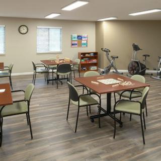 A multipurpose activity room with tables, chairs, and exercise equipment.