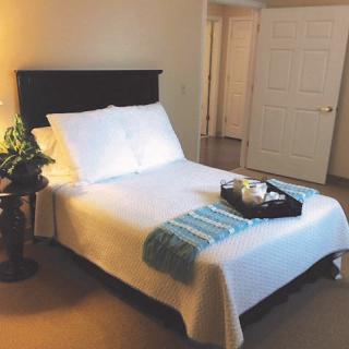 A neatly arranged bedroom with a bed, pillows, and a tray on top.