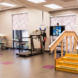 A rehabilitation facility featuring exercise equipment and a mini staircase for physical therapy purposes.