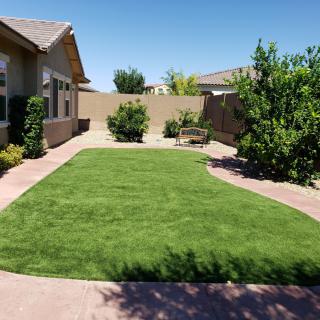 A sunny suburban backyard with a well-maintained lawn and patio area.