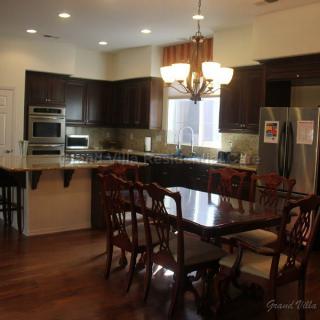 A modern kitchen with dark wood cabinets and a dining area featuring a chandelier.